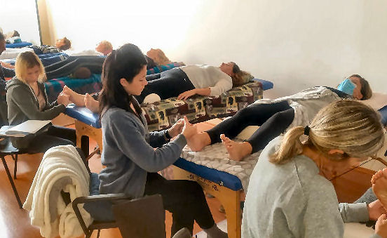 Studenti on zon su school durante un'esercitazione pratica di riflessologia plantare