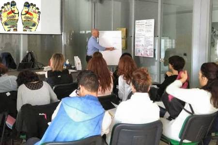 tudenti e insegnante durante una lezione teorica del corso di riflessologia a Roma.